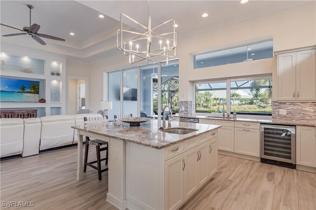 kitchen featuring wine cooler, a sink, open floor plan, tasteful backsplash, and crown molding