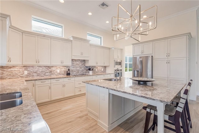 kitchen featuring a sink, visible vents, ornamental molding, appliances with stainless steel finishes, and decorative backsplash