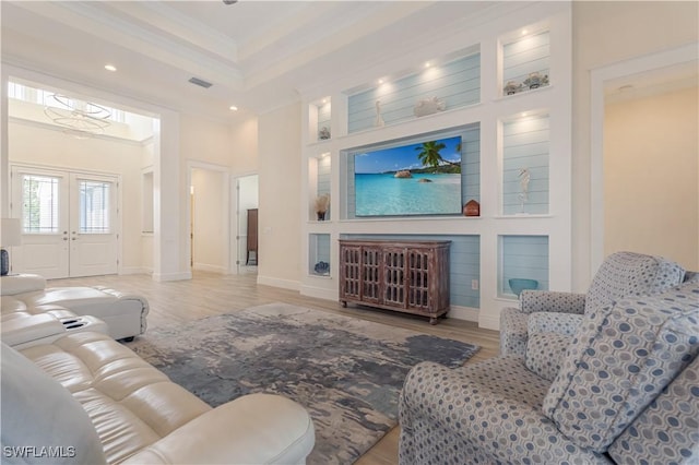 living room with visible vents, french doors, light wood-type flooring, a tray ceiling, and crown molding