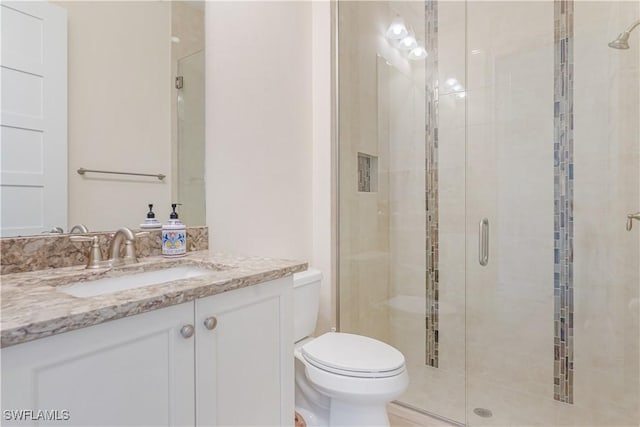 bathroom with toilet, a stall shower, and vanity