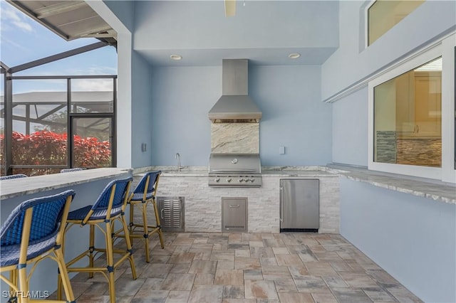 view of patio with glass enclosure, an outdoor kitchen, outdoor wet bar, a sink, and grilling area