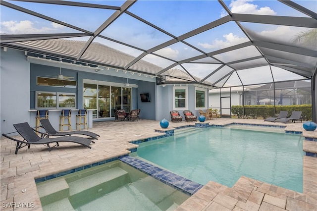 view of swimming pool featuring a patio area, a pool with connected hot tub, glass enclosure, and outdoor dry bar