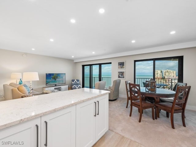 kitchen with light stone counters, a wealth of natural light, open floor plan, and white cabinets