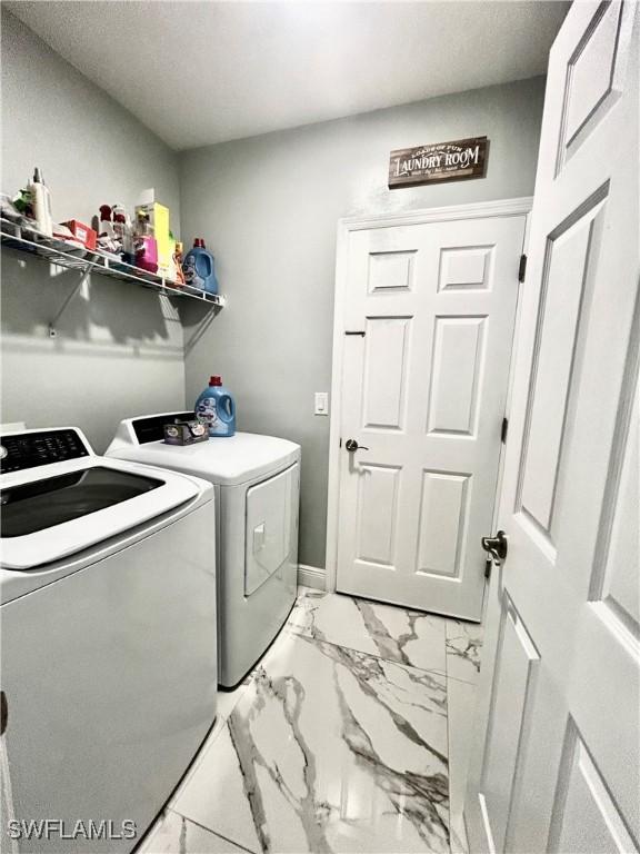 washroom with marble finish floor, laundry area, independent washer and dryer, and baseboards