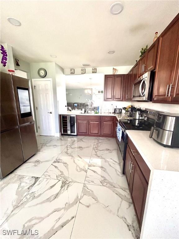 kitchen featuring marble finish floor, light countertops, appliances with stainless steel finishes, a sink, and beverage cooler