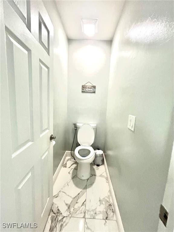 bathroom featuring marble finish floor, toilet, and baseboards