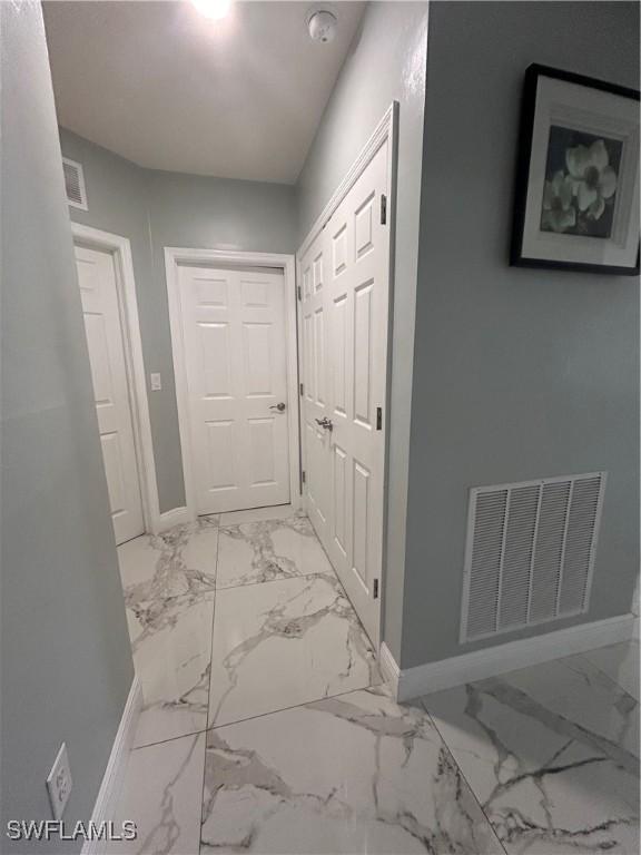 hallway featuring marble finish floor, baseboards, and visible vents