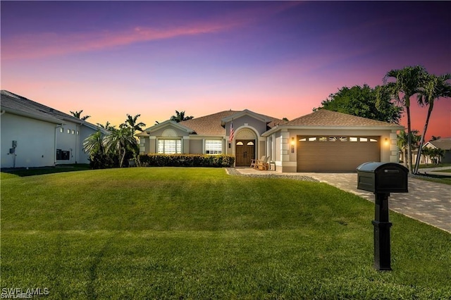 single story home with a yard, driveway, an attached garage, and stucco siding