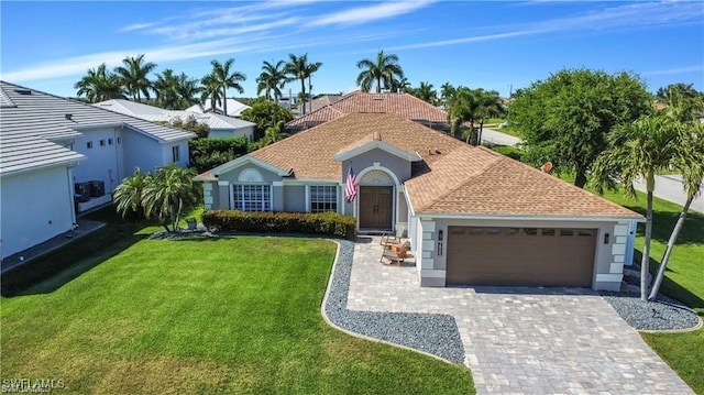 view of front of home with a garage, decorative driveway, and a front yard