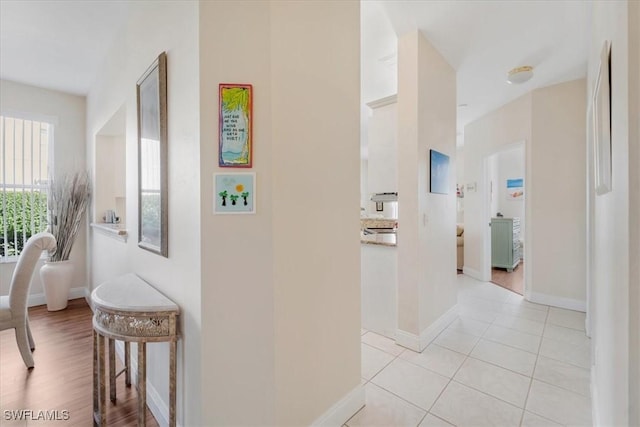 hall featuring light tile patterned flooring and baseboards