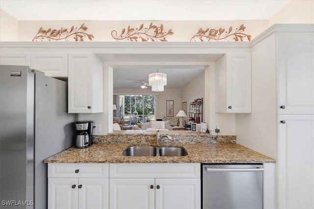 kitchen featuring stainless steel appliances, a ceiling fan, white cabinetry, a sink, and light stone countertops