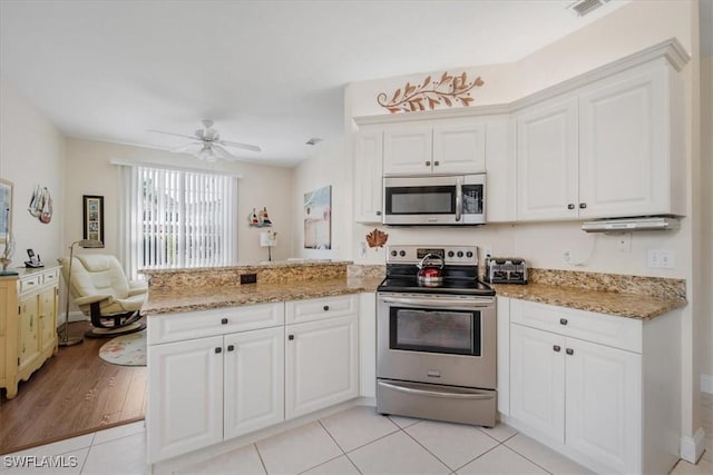 kitchen with appliances with stainless steel finishes, a ceiling fan, white cabinets, light stone countertops, and a peninsula