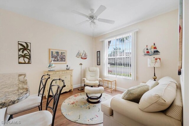 living area featuring ceiling fan, wood finished floors, and baseboards