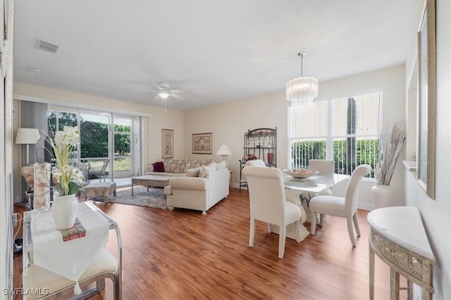 dining room featuring visible vents, wood finished floors, and ceiling fan with notable chandelier