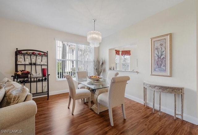 dining space featuring a notable chandelier, baseboards, and wood finished floors