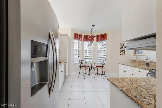 kitchen featuring light stone counters, light tile patterned flooring, white cabinetry, appliances with stainless steel finishes, and pendant lighting