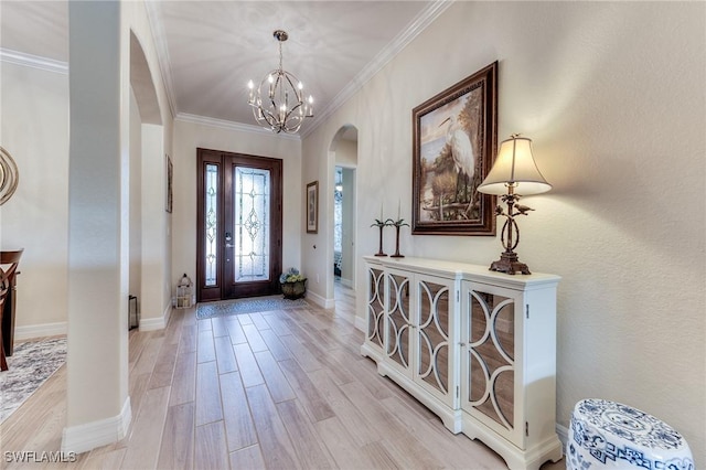 entrance foyer with baseboards, arched walkways, an inviting chandelier, crown molding, and light wood-style floors