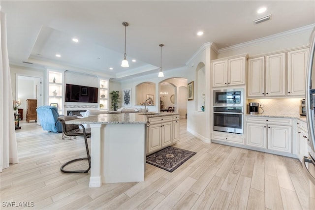 kitchen featuring visible vents, arched walkways, a sink, ornamental molding, and stainless steel appliances