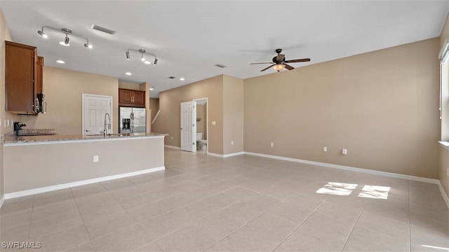 interior space with light tile patterned floors, a sink, a ceiling fan, visible vents, and baseboards