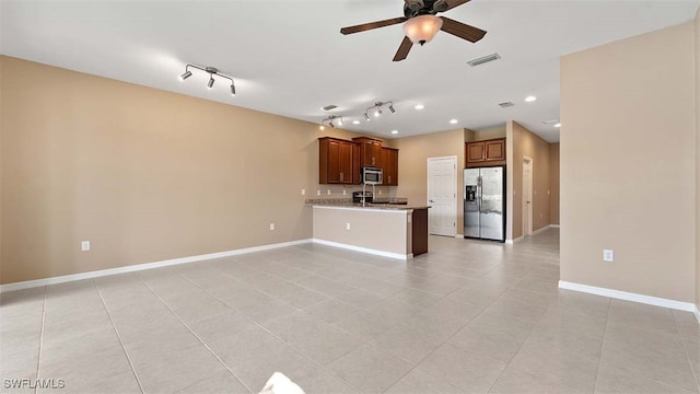 interior space featuring visible vents, appliances with stainless steel finishes, brown cabinets, a peninsula, and light stone countertops