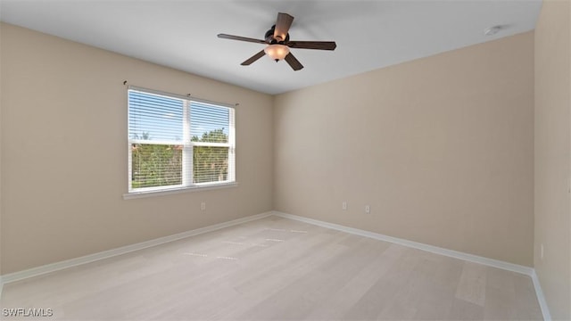 empty room with light wood finished floors, a ceiling fan, and baseboards