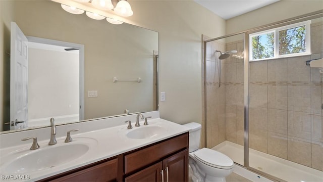 bathroom with double vanity, a sink, toilet, and a shower stall