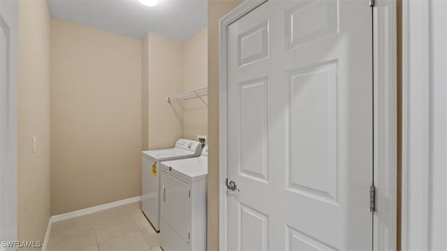 laundry room featuring laundry area, washer and clothes dryer, baseboards, and light tile patterned floors