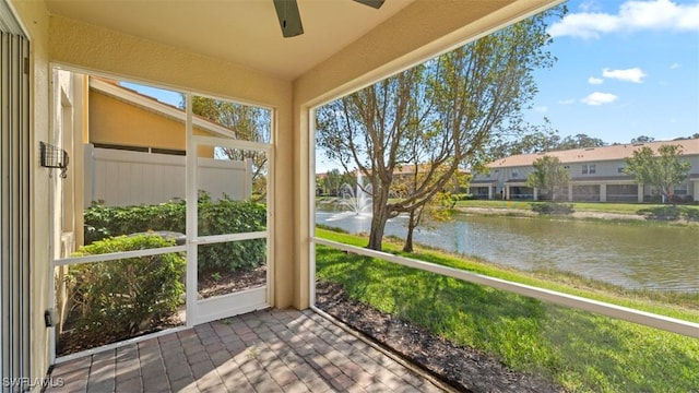 unfurnished sunroom featuring plenty of natural light, a water view, and a ceiling fan