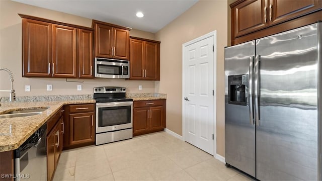 kitchen featuring recessed lighting, appliances with stainless steel finishes, a sink, light stone countertops, and baseboards