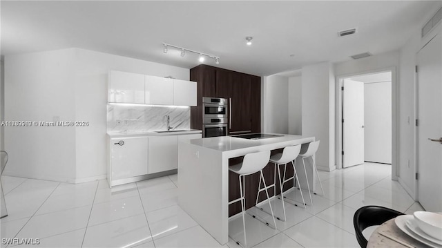 kitchen featuring dark brown cabinetry, white cabinets, light countertops, a center island, and modern cabinets