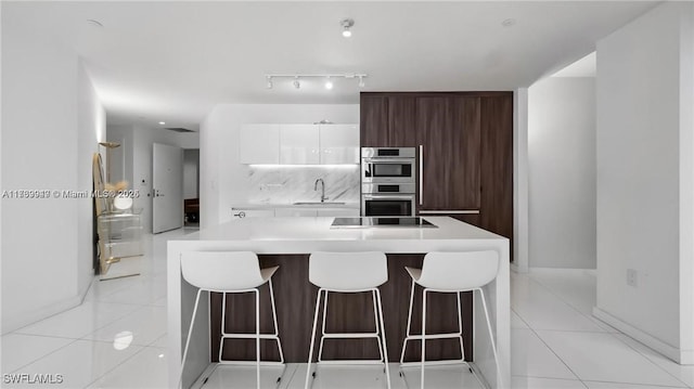 kitchen featuring light tile patterned floors, white cabinets, modern cabinets, light countertops, and a sink