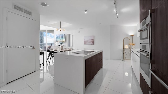 kitchen featuring visible vents, modern cabinets, a kitchen island, black electric cooktop, and stainless steel oven