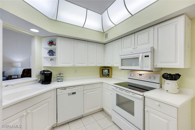 kitchen with visible vents, light tile patterned flooring, a sink, white cabinets, and white appliances