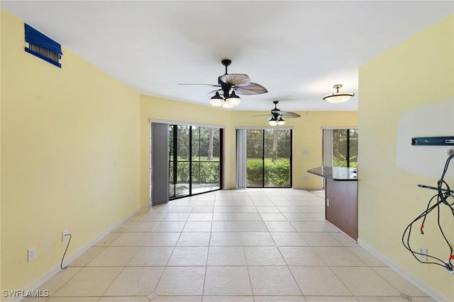 unfurnished room with light tile patterned floors, a ceiling fan, and baseboards