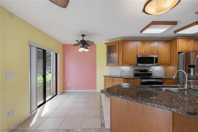 kitchen featuring brown cabinets, a sink, backsplash, stainless steel appliances, and light tile patterned floors