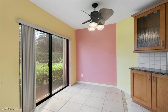 unfurnished dining area featuring light tile patterned floors, baseboards, and a ceiling fan