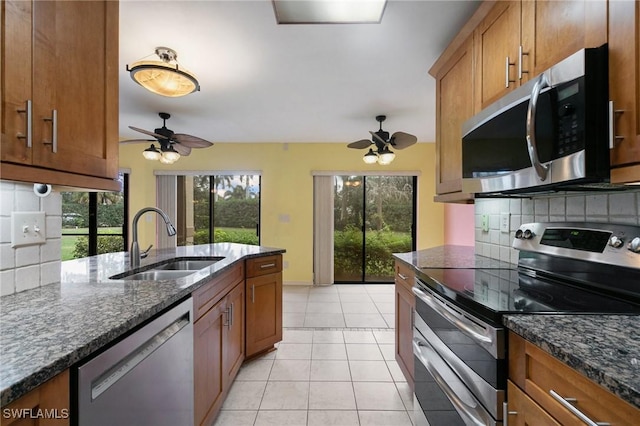 kitchen featuring a sink, brown cabinets, appliances with stainless steel finishes, and light tile patterned flooring