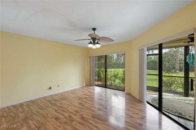 spare room featuring baseboards, wood finished floors, and a ceiling fan