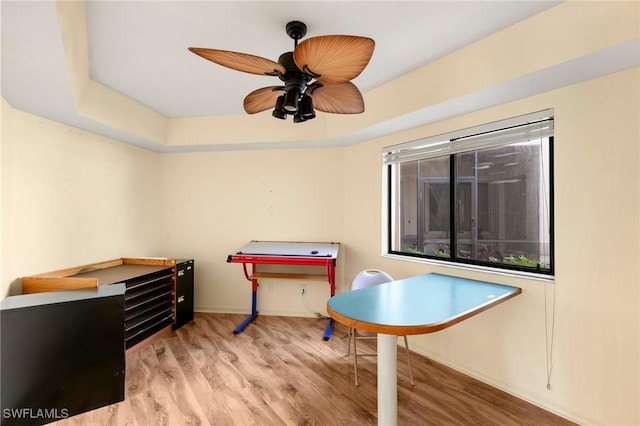 game room featuring ceiling fan, a tray ceiling, and wood finished floors