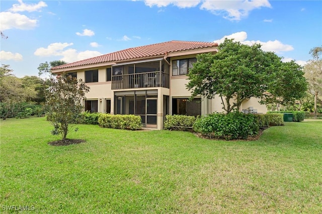 rear view of property featuring a balcony, a yard, a sunroom, and stucco siding