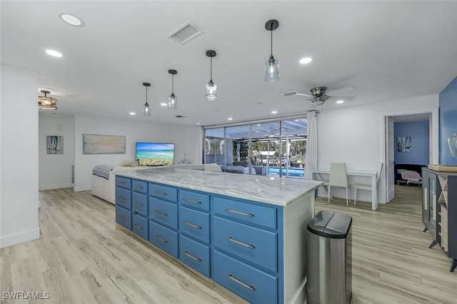 kitchen with blue cabinets, visible vents, open floor plan, and light wood finished floors