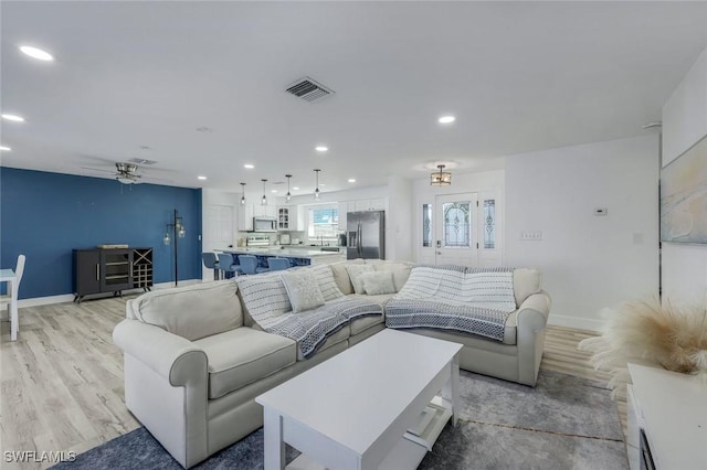 living area featuring visible vents, baseboards, recessed lighting, light wood-style floors, and a ceiling fan