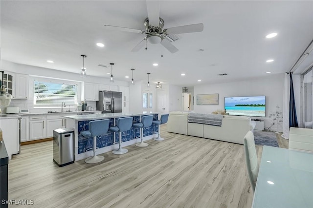 kitchen with a breakfast bar, a sink, a kitchen island, stainless steel fridge, and white cabinets