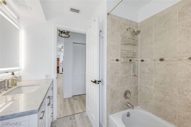 bathroom with vanity, wood finished floors, visible vents, and shower / washtub combination