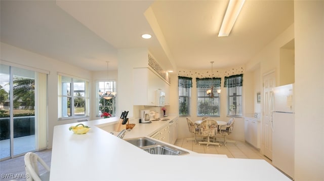 kitchen featuring white appliances, a wealth of natural light, a sink, and an inviting chandelier