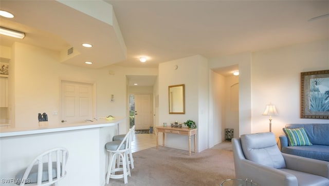 kitchen featuring visible vents, light colored carpet, open floor plan, a kitchen breakfast bar, and recessed lighting