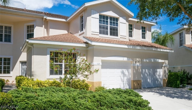 view of front facade with a shingled roof, driveway, an attached garage, and stucco siding