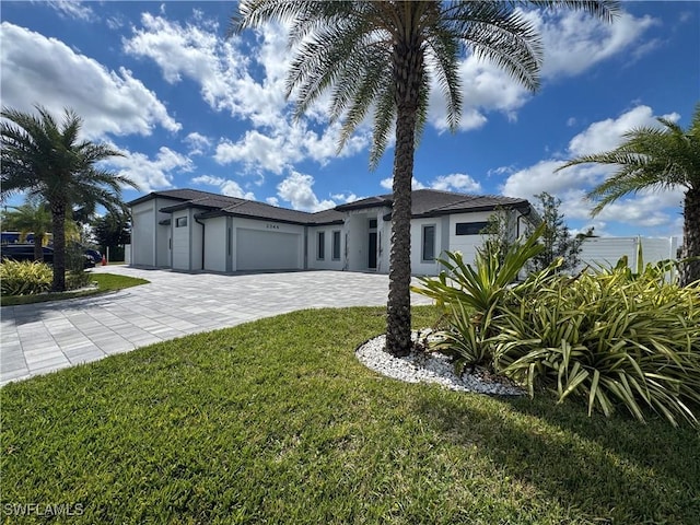 view of front of home featuring a garage, a front lawn, decorative driveway, and stucco siding