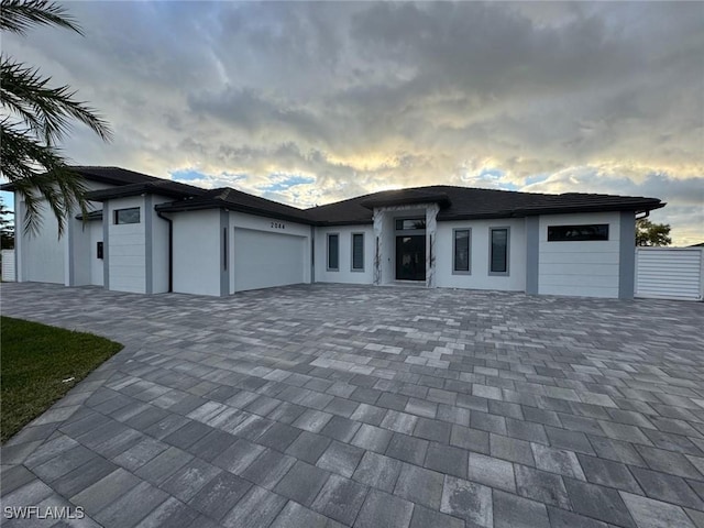 prairie-style house featuring a garage, decorative driveway, and stucco siding