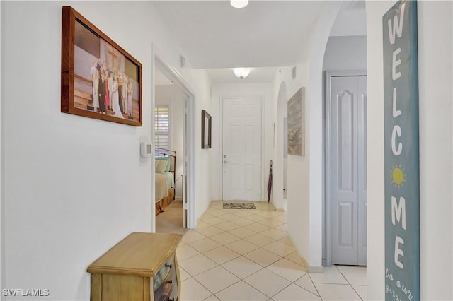 corridor with light tile patterned floors and arched walkways